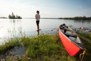 Woman standing in the shore water and holding a rope.